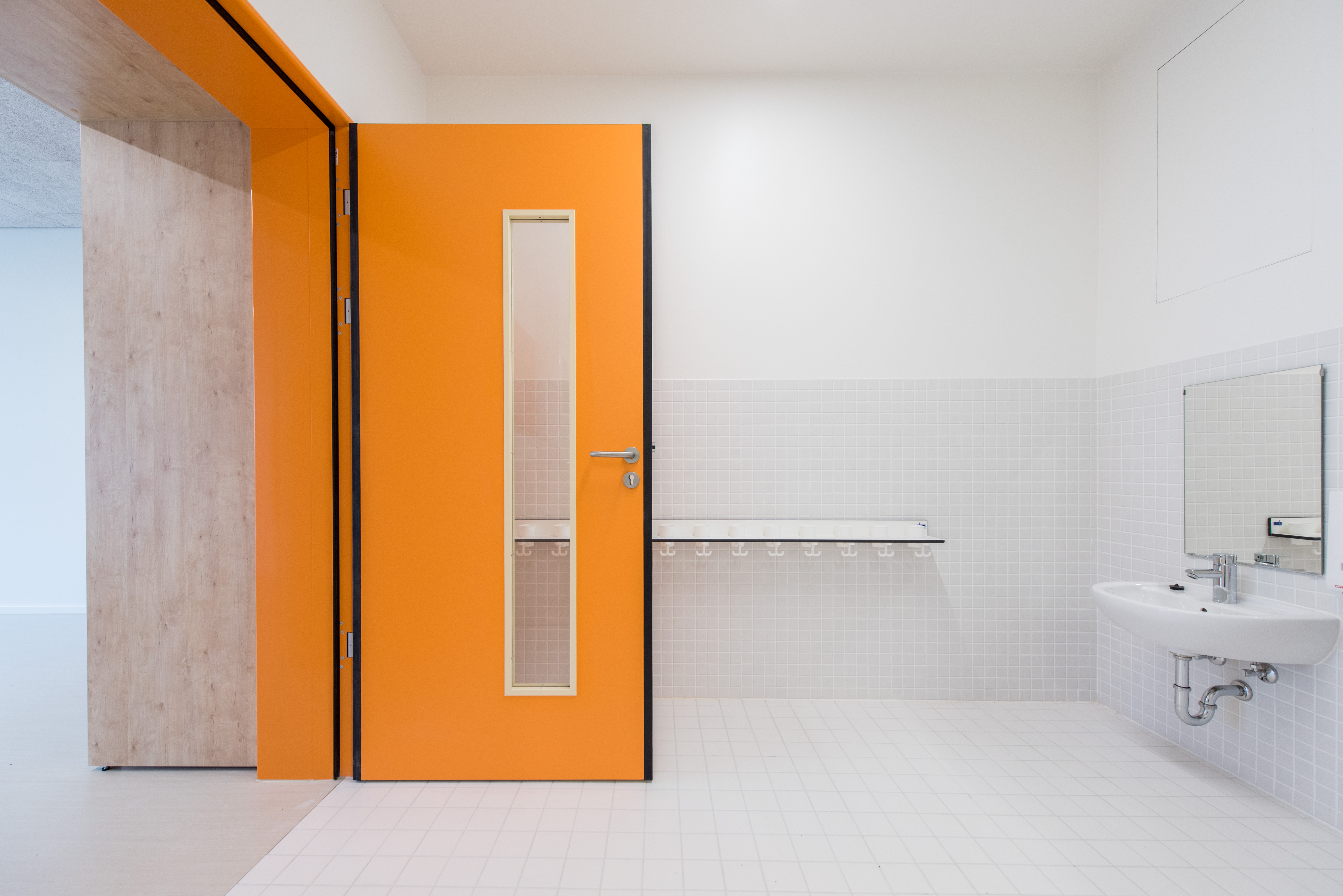 orangefarbene Fingerschutztür mit Lichtausschnitt im Nassraum